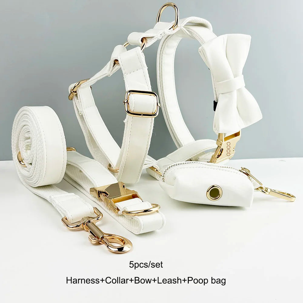 Handmade leather pet accessories set in white, featuring engravable collar, harness, leash, bow tie, and bag.