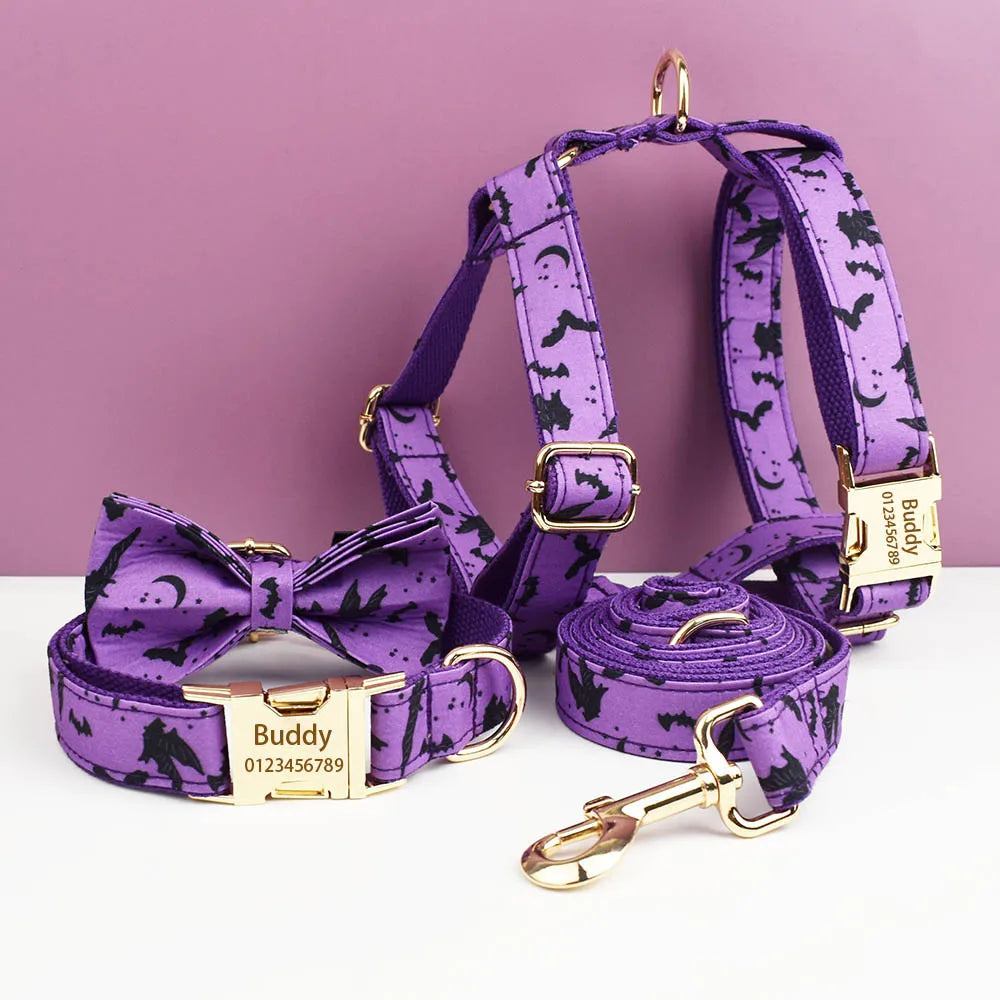 Purple dog harness, leash, and bow tie set with gold hardware on a white surface against a pink background.