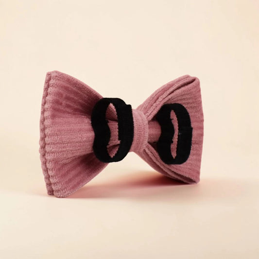 Pink corduroy detachable dog bow tie on a beige background