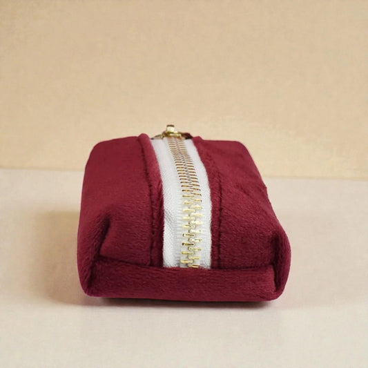 Red dog poop bag holder with a gold zip on a beige background