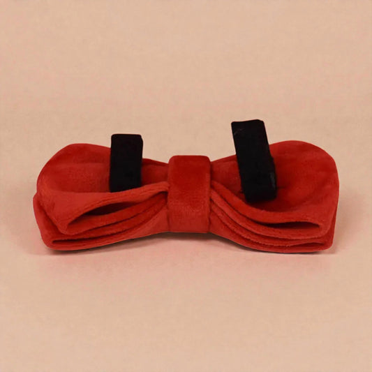 Red bow tie with black straps on a beige background