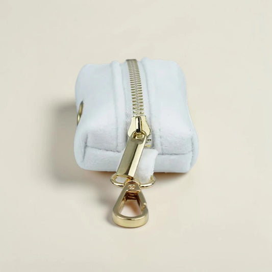 Velvet white dog poop bag holder with gold zip on a beige background