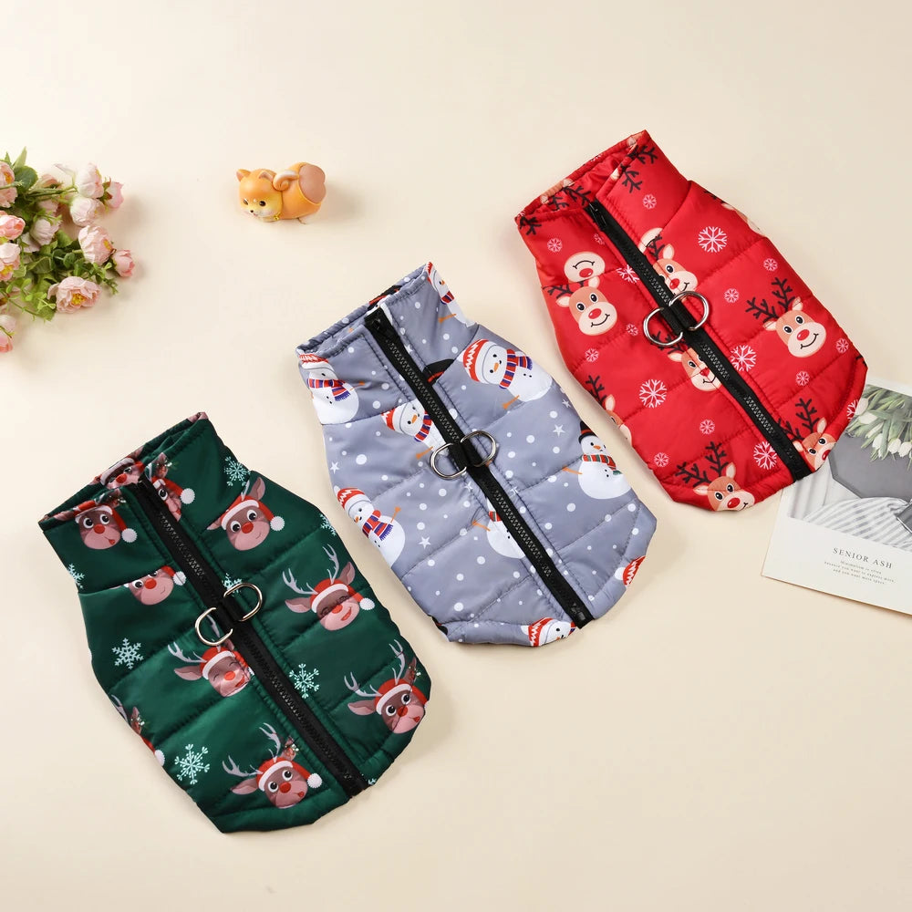 Three festive dog vests in red, green, and blue with reindeer and snowman patterns on a beige background.