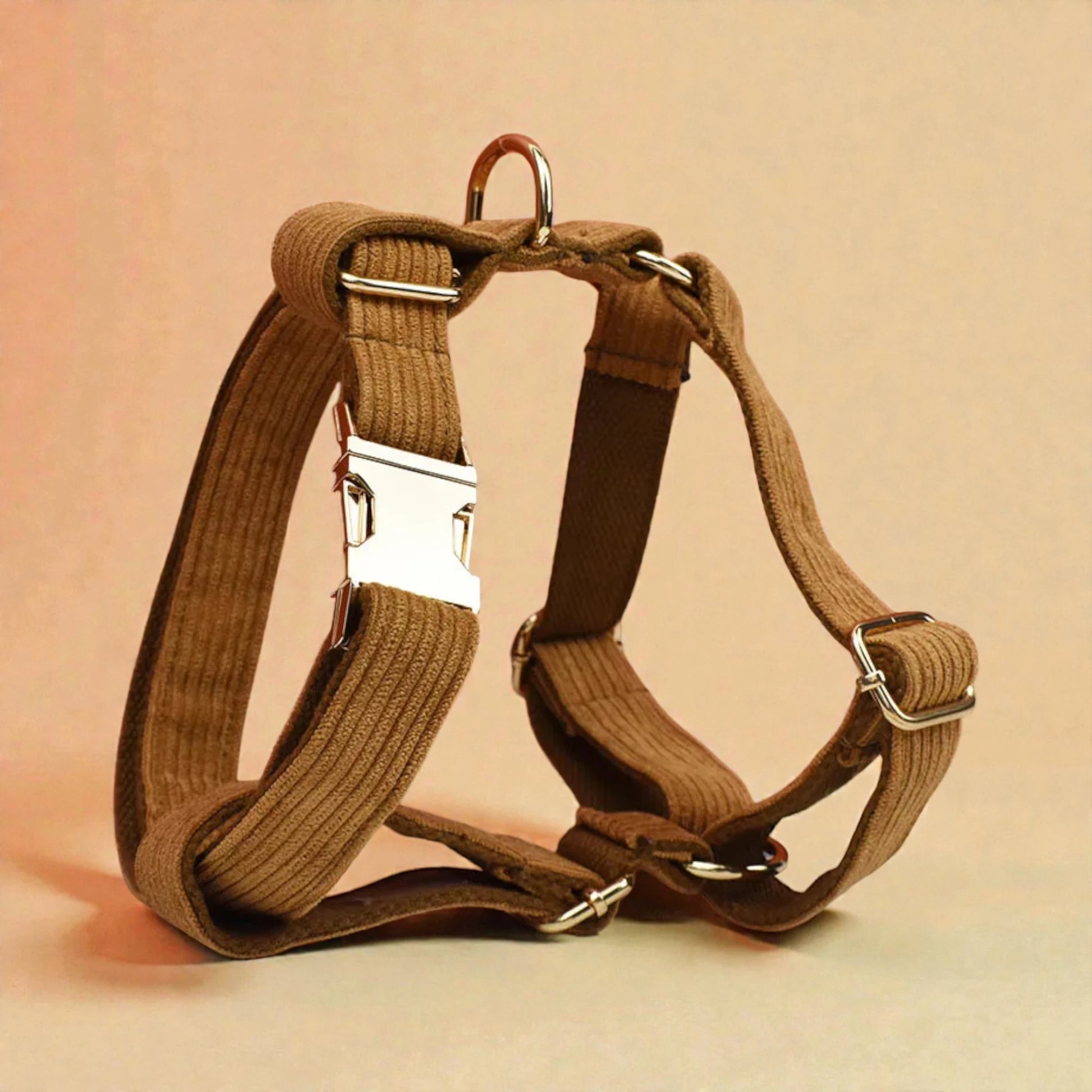 Brown dog harness with metal buckles on a beige background