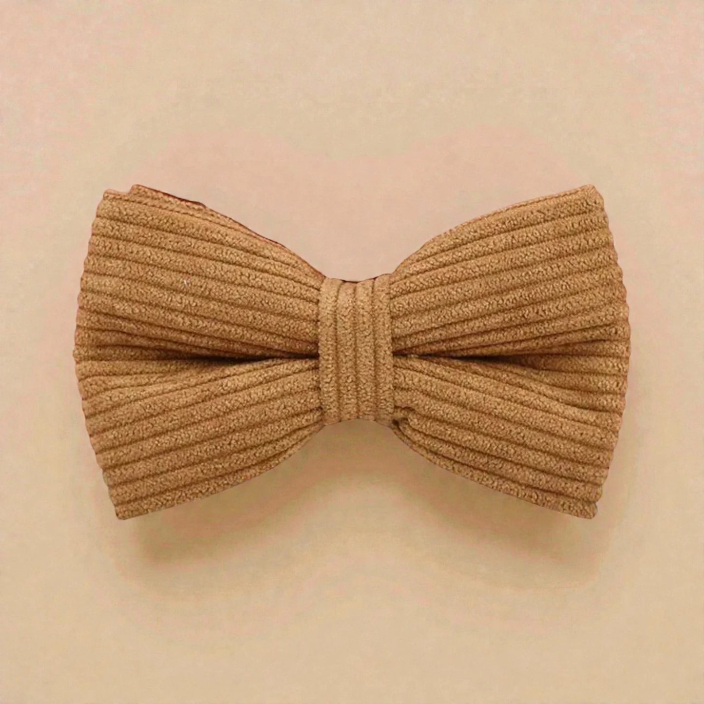Brown corduroy bow tie on a beige background