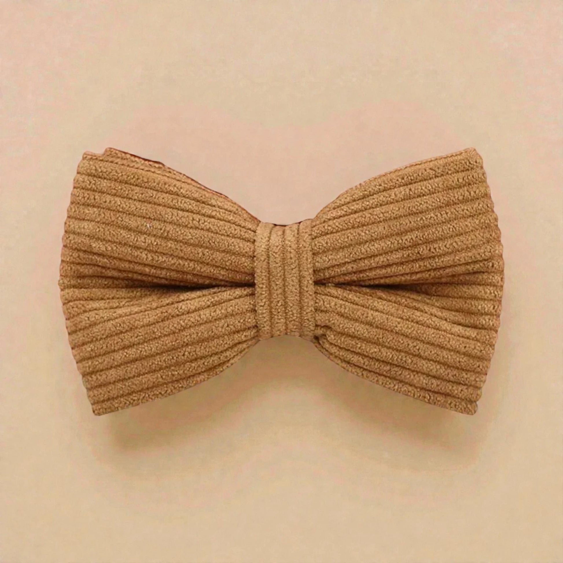Brown corduroy bow tie on a beige background