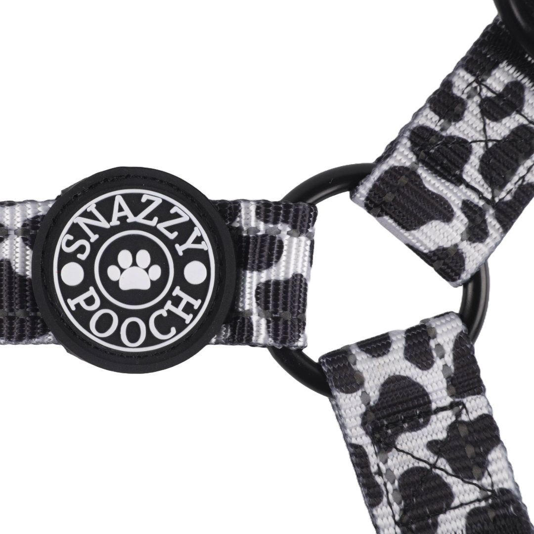 Adjustable cow print dog harness with Snazzy Pooch branding and 3M reflective stitching for safety.