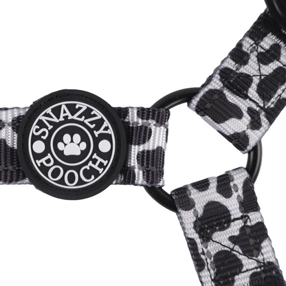 Adjustable cow print dog harness with Snazzy Pooch branding and 3M reflective stitching for safety.