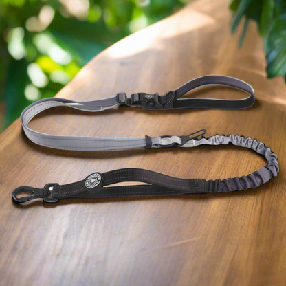 Two dog leashes, one gray and one black, lie on a wooden surface.