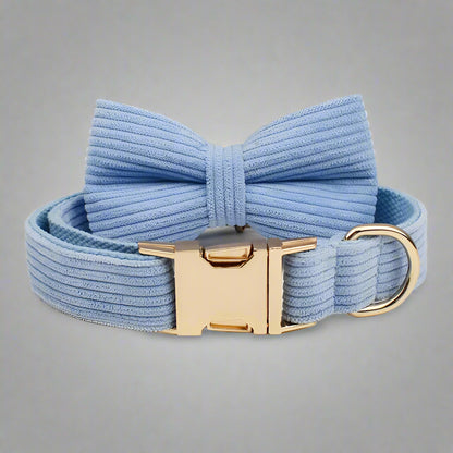 Blue dog collar with a large bow and gold clasp on a light gray background