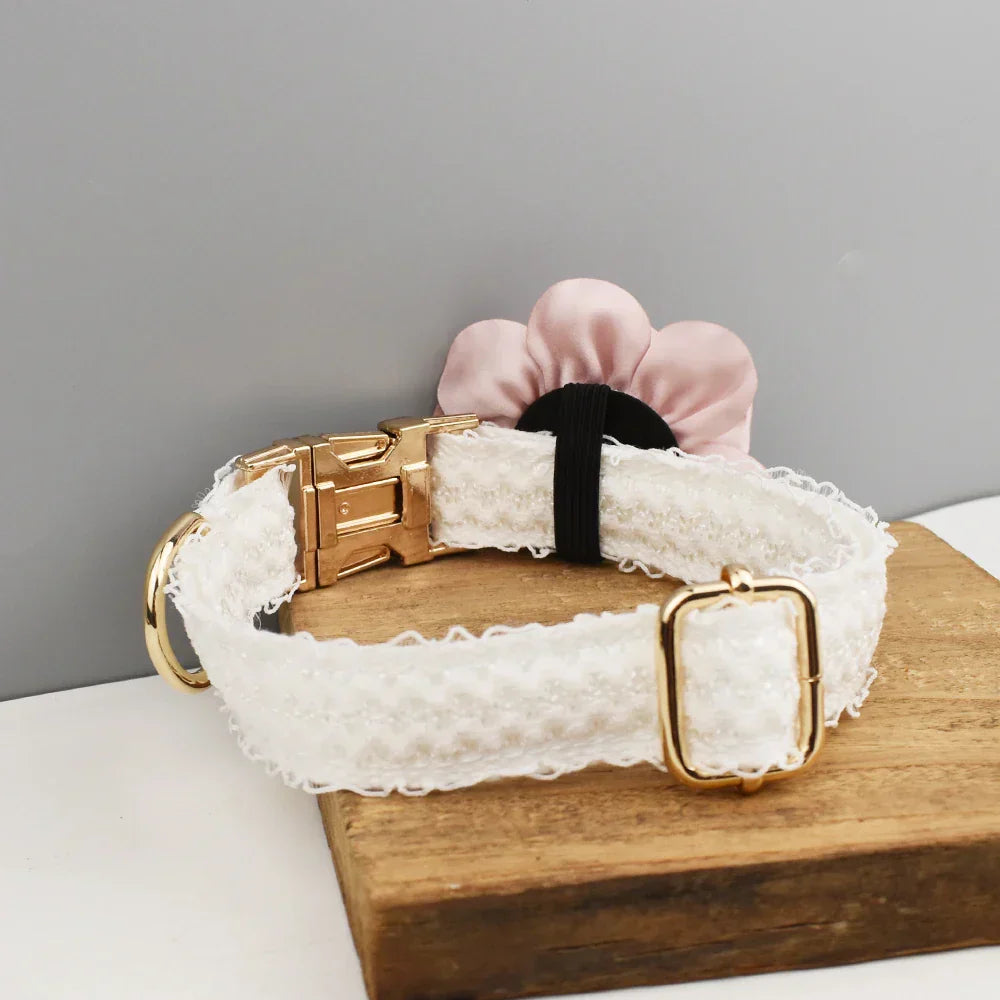 White lace dog collar with gold-tone hardware on wood surface, elegant wedding attire for dogs.