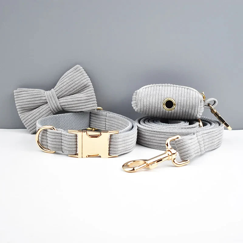 Luxury pet accessories in light grey corduroy fabric, featuring a bowtie, collar, and lead set with gold hardware.