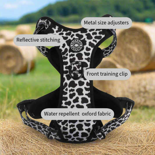 Black and white cow print dog harness with reflective stitching.