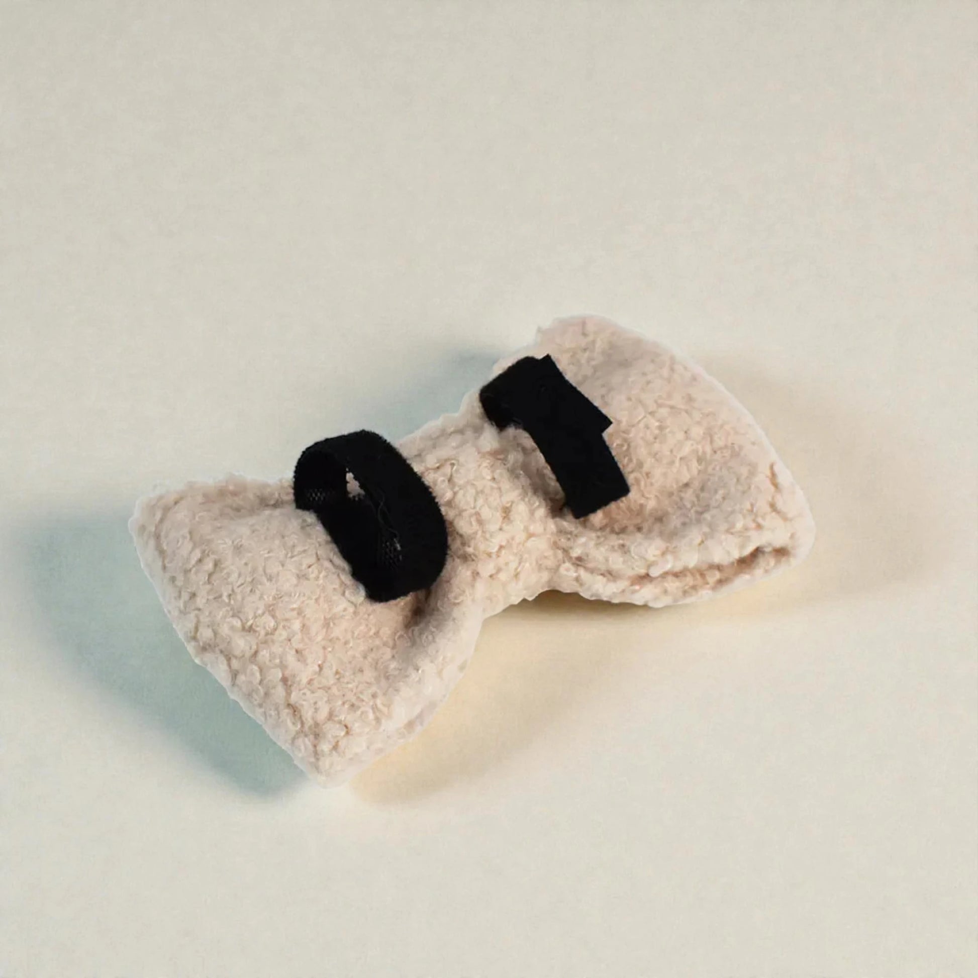 beige bow tie with black straps on a light background