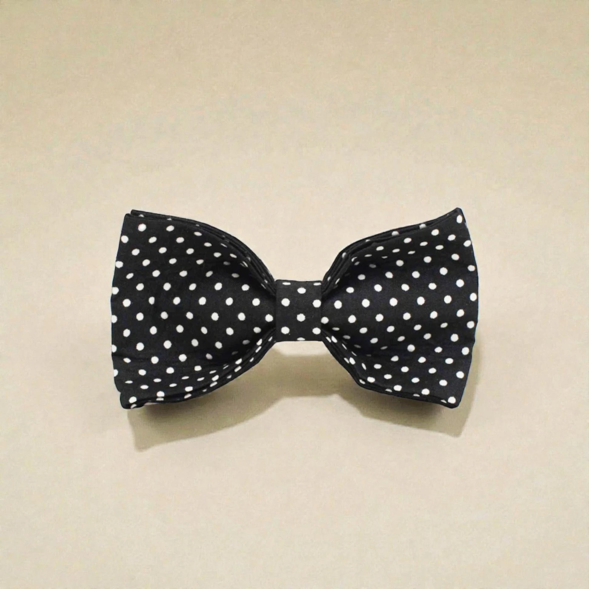 Black dog bow tie with white polka dots on a beige background