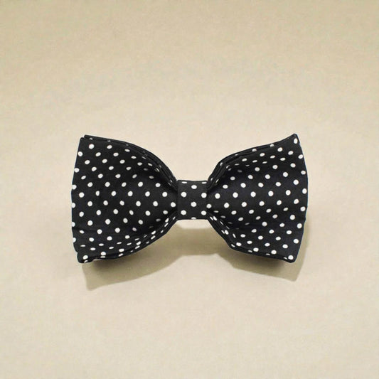Black dog bow tie with white polka dots on a beige background