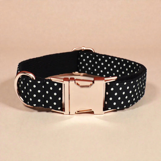 Black polka dot dog collar with gold buckle on a beige background