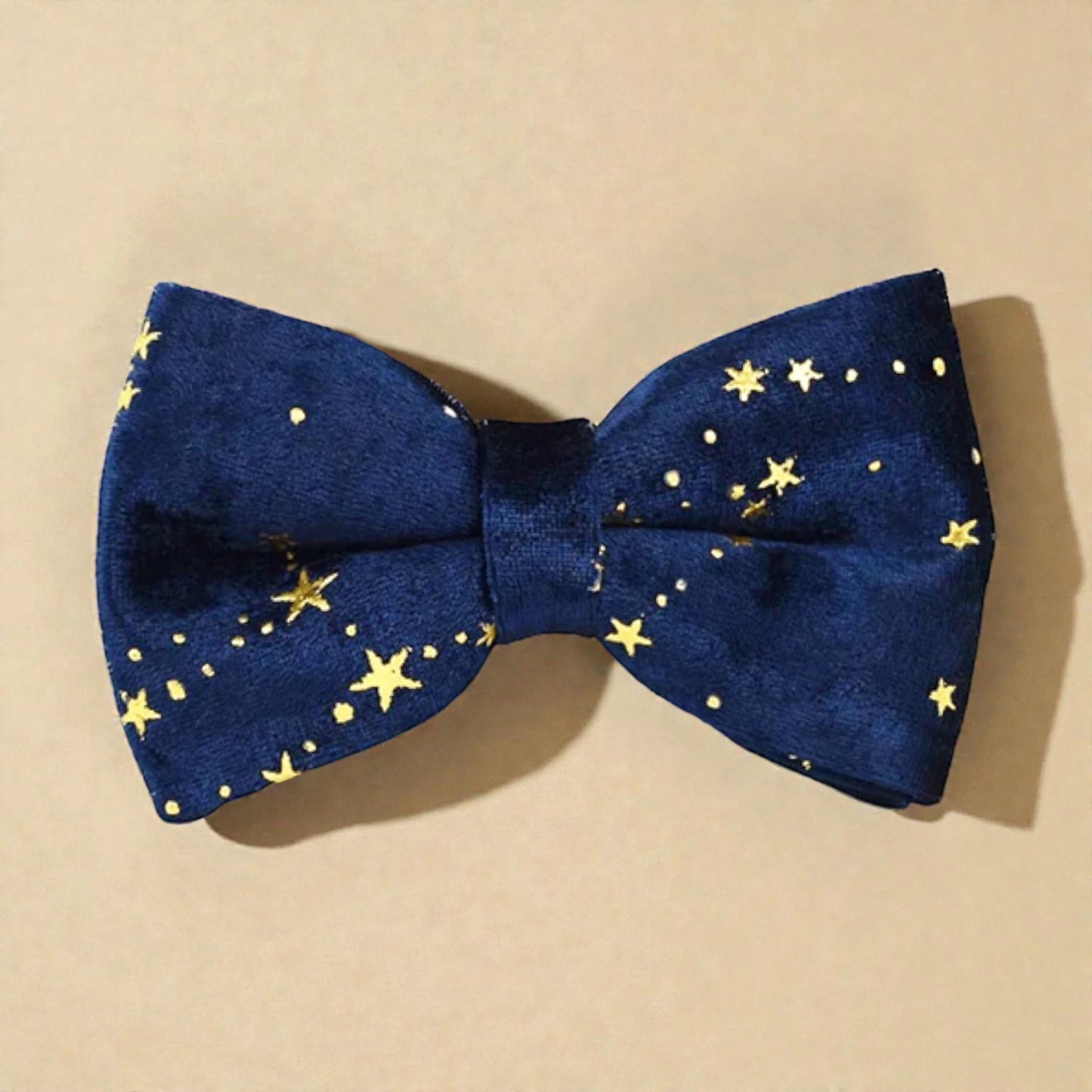 Blue bow tie with gold star pattern on a beige background