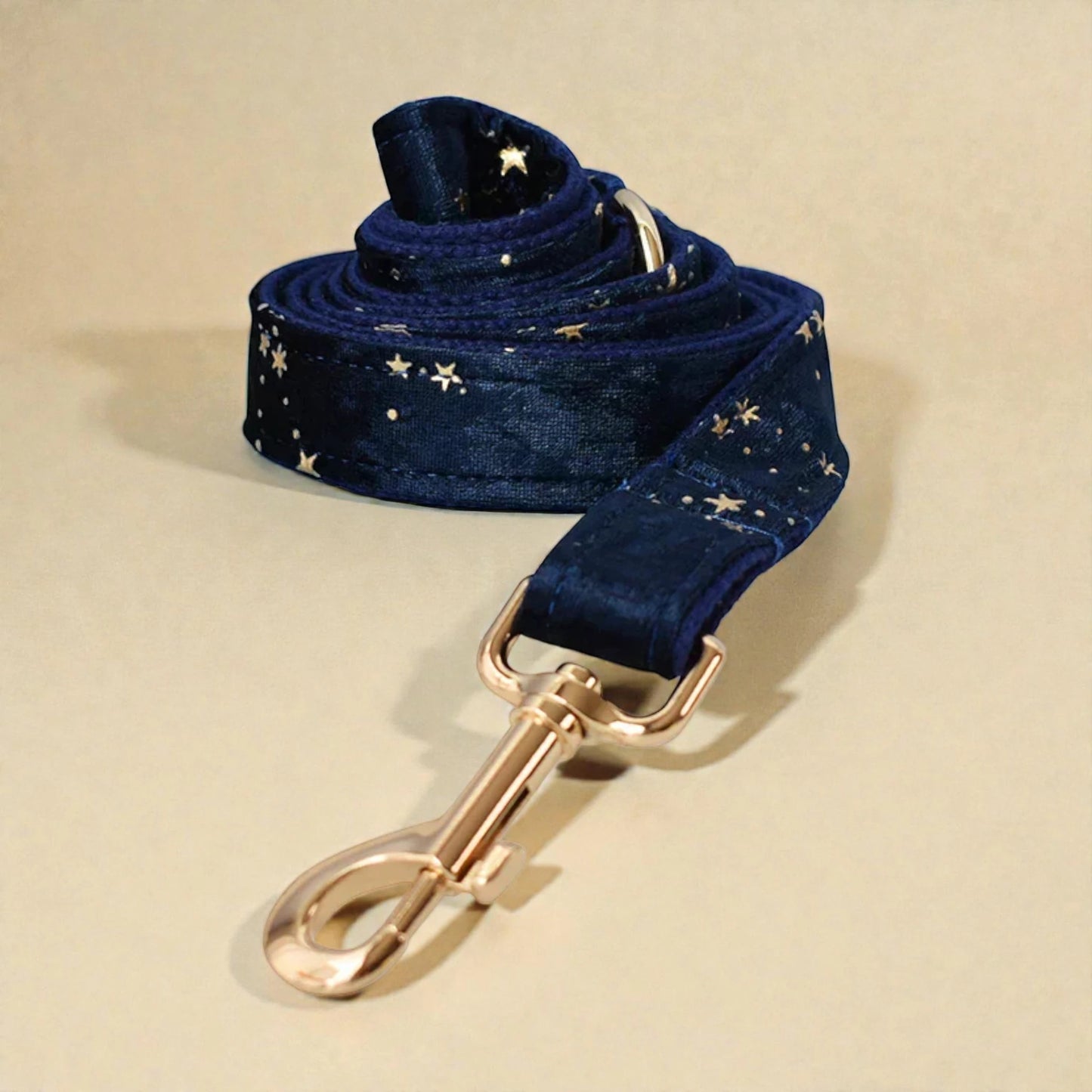 Navy blue dog lead with gold star pattern and gold clasp on beige background