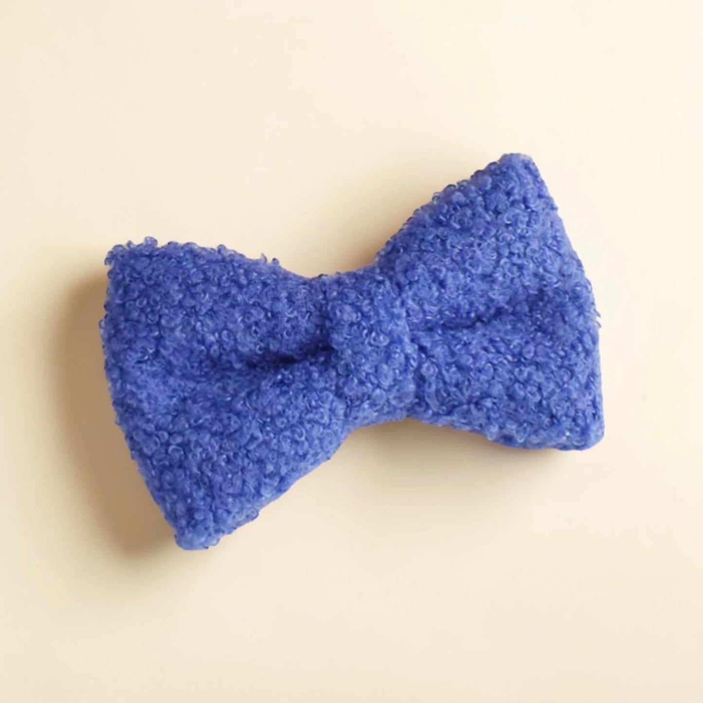 Blue teddy fleece dog bow on a beige background