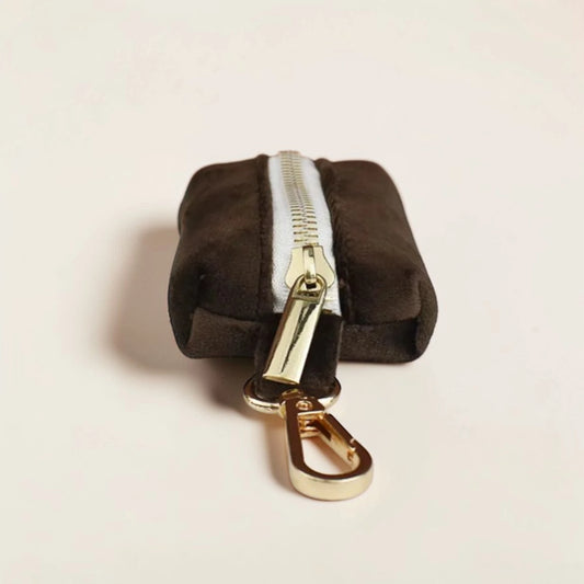 Brown dog poop bag holder with gold zip and clip on a beige background