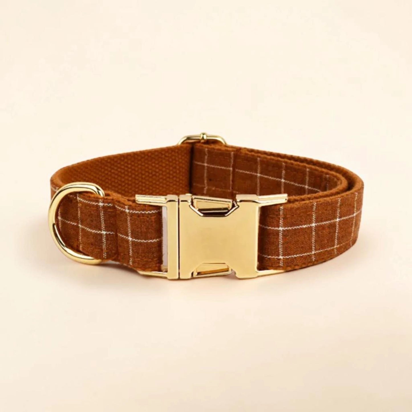 Brown plaid dog collar with a gold buckle on a beige background