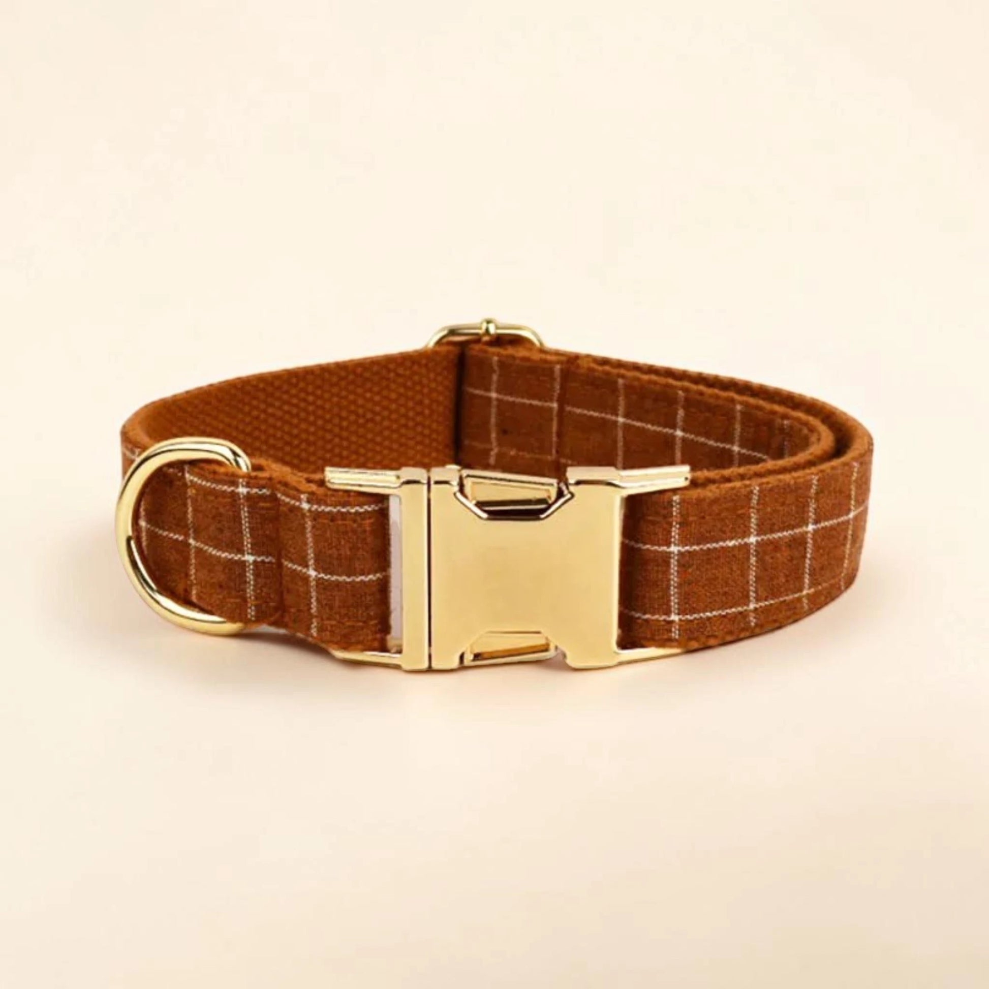 Brown plaid dog collar with a gold buckle on a beige background