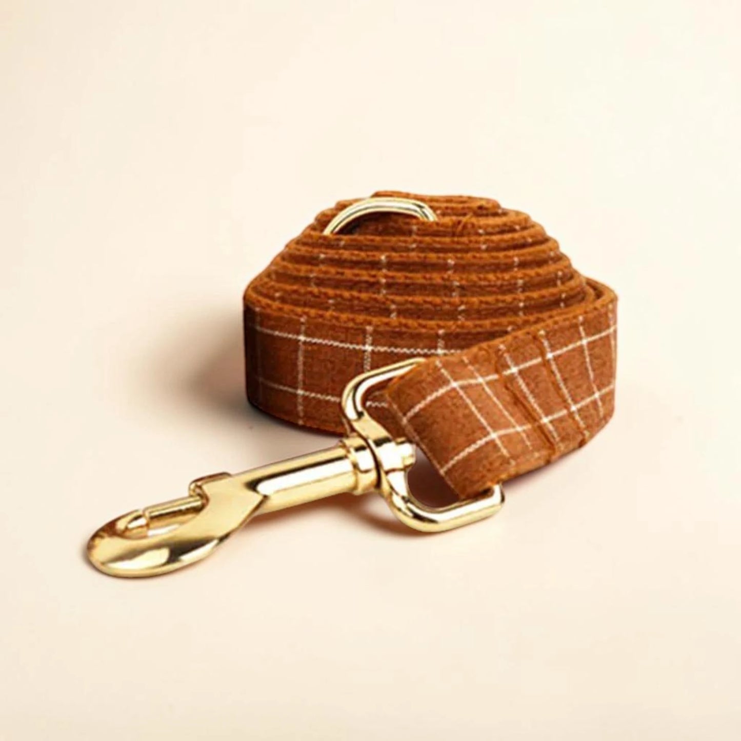 Brown plaid dog lead with gold clip on a beige background