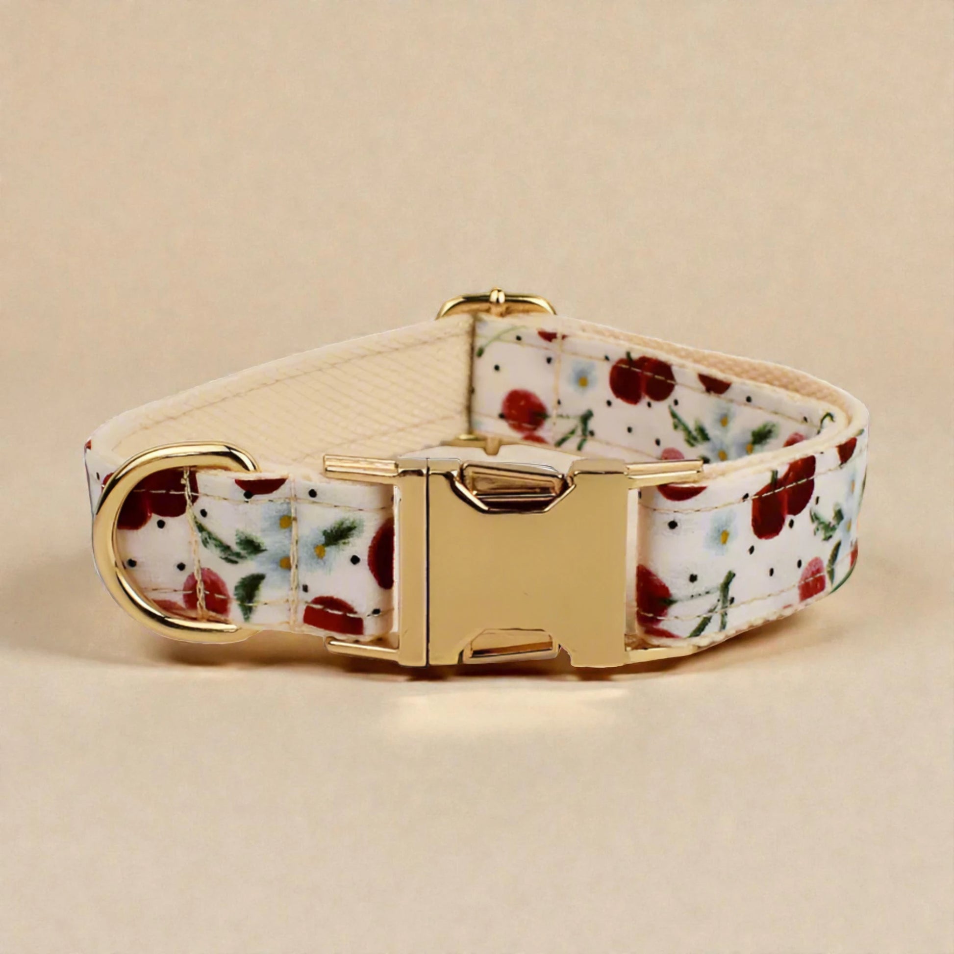 Floral-patterned red cherry dog collar with gold buckle on a beige background