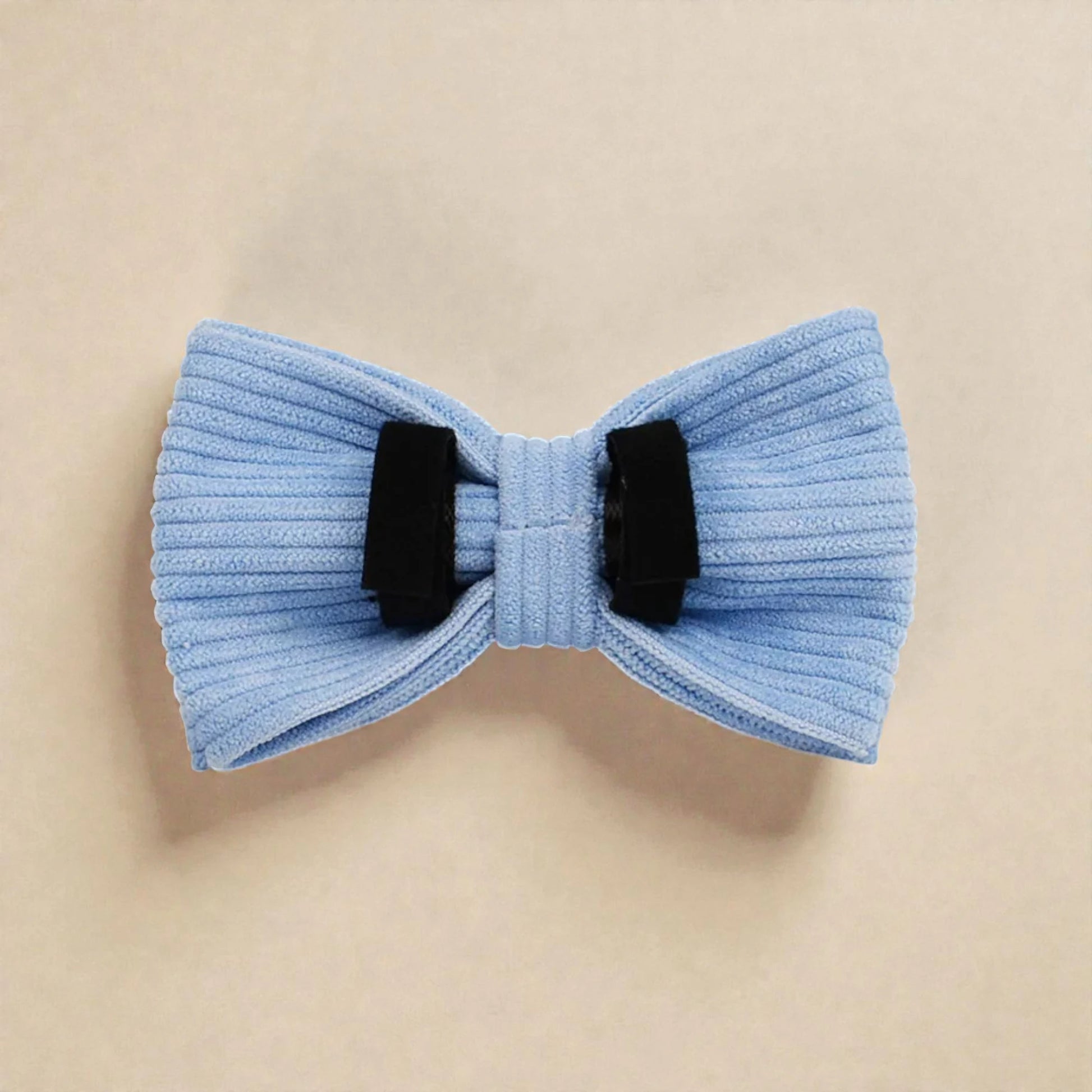 Light blue bow tie with black velcro loops on a beige background