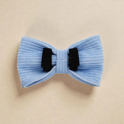 Light blue bow tie with black velcro loops on a beige background