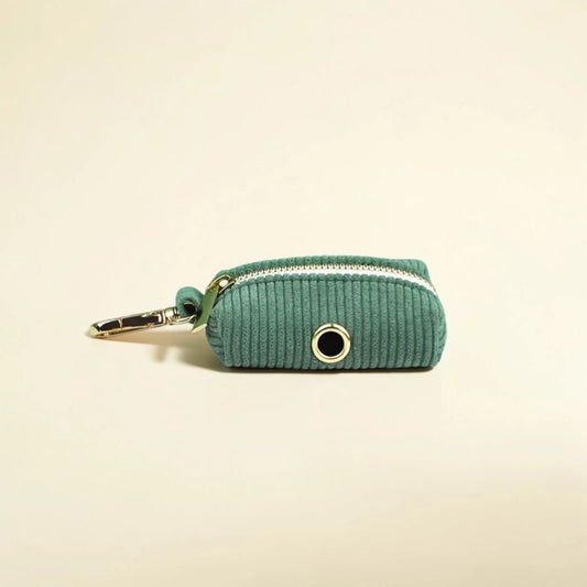 Green corduroy dog poop bag holder with a zip on a beige background
