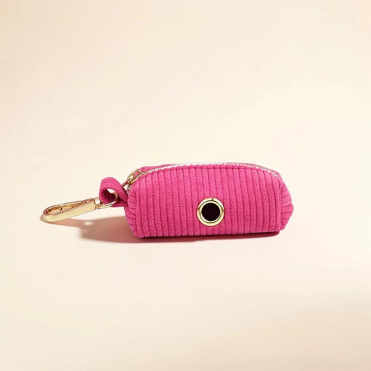 Pink dog poop bag holder with gold zip and clip on a beige background