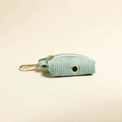 Light green corduroy dog poop bag holder with gold zip on a beige background