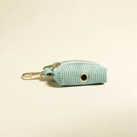 Light green corduroy dog poop bag holder with gold zip on a beige background