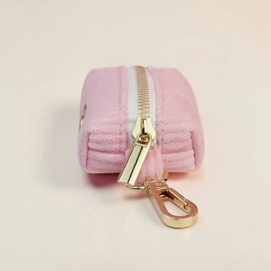 Pink dog poop bag holder with gold zip and clip on a beige background