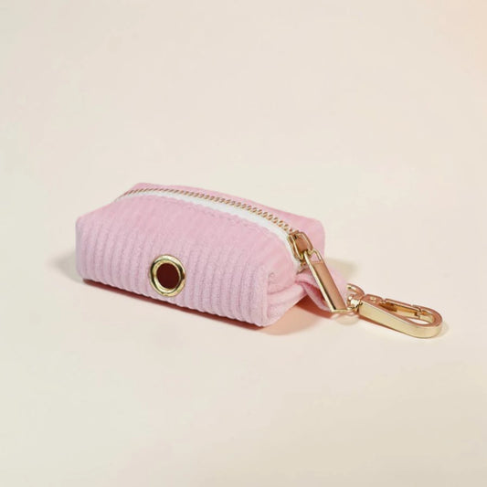 Pink dog poop bag holder with gold zip and clip on a beige background