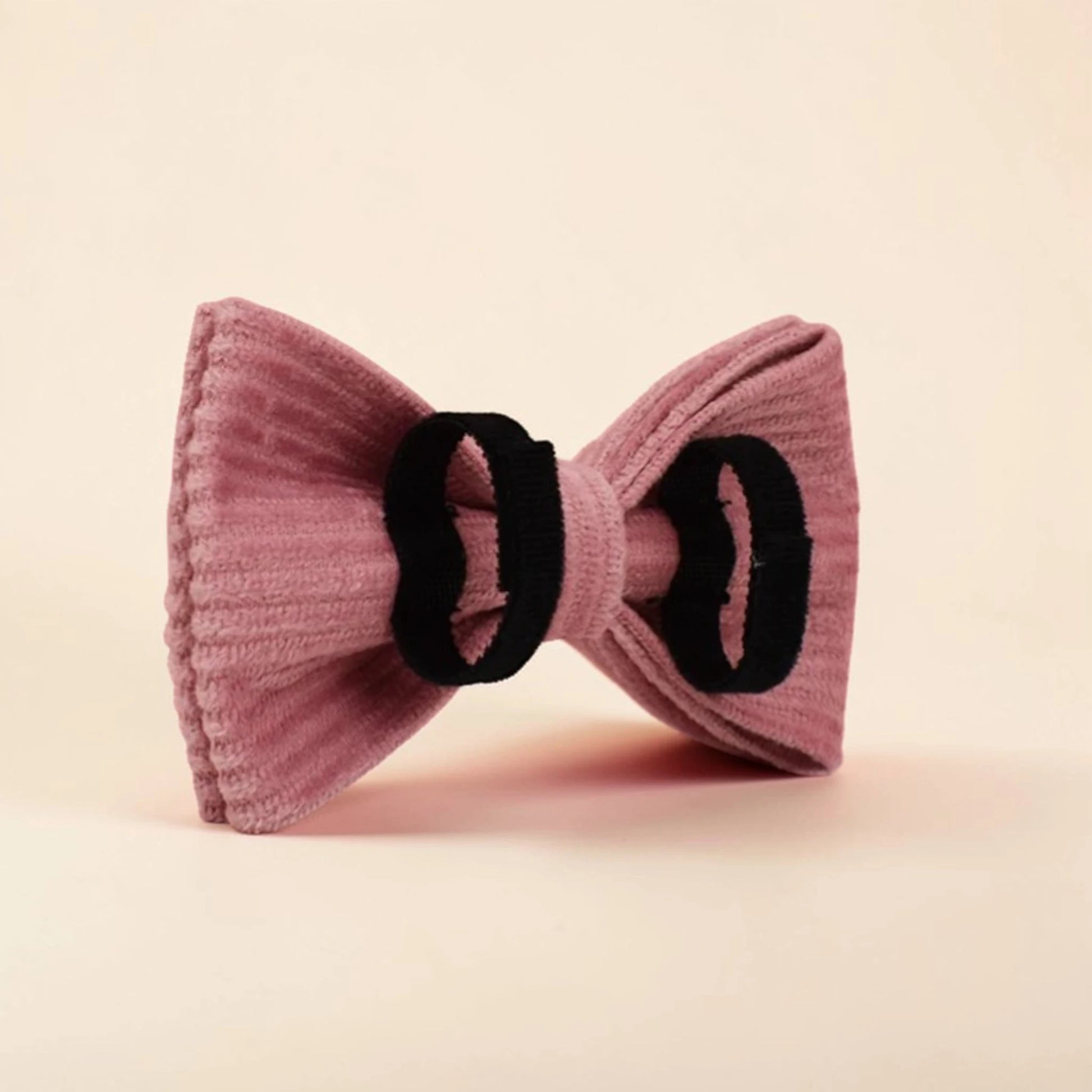 Pink corduroy detachable dog bow tie on a beige background