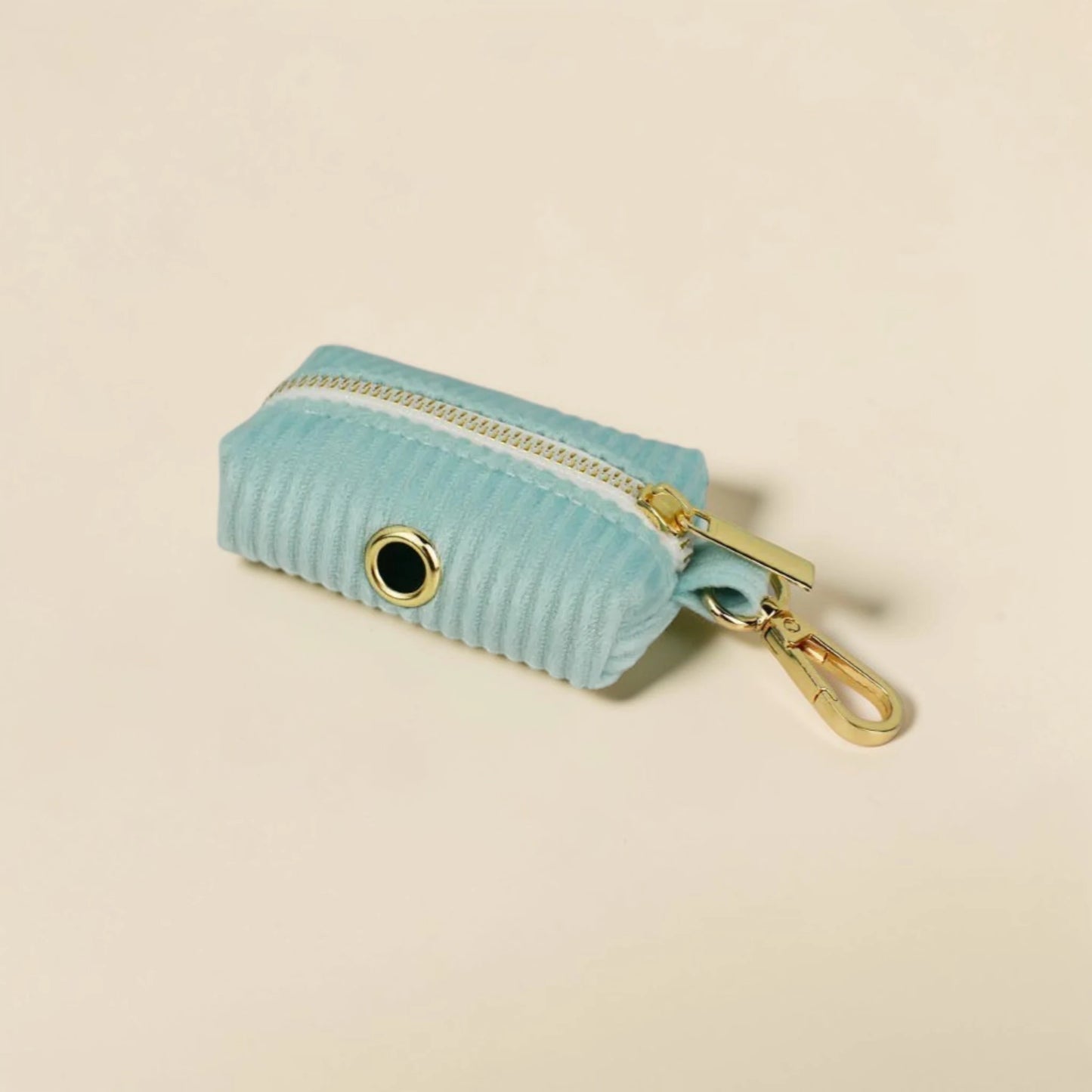 Soft mint green dog poop bag holder with gold zip and clip on a beige background