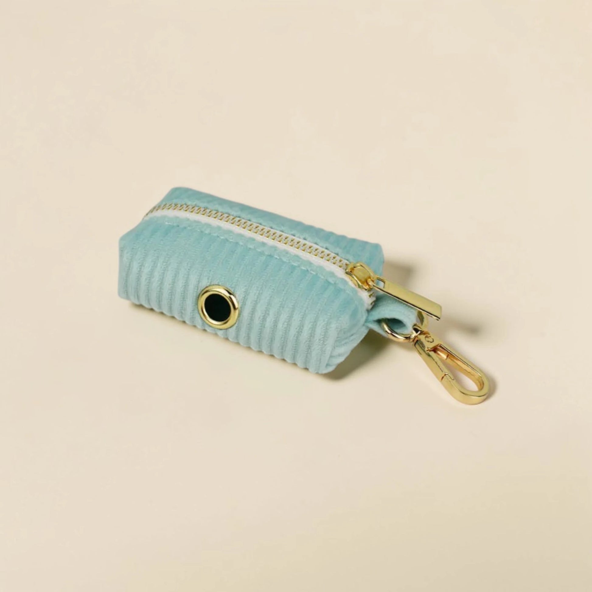 Soft mint green dog poop bag holder with gold zip and clip on a beige background