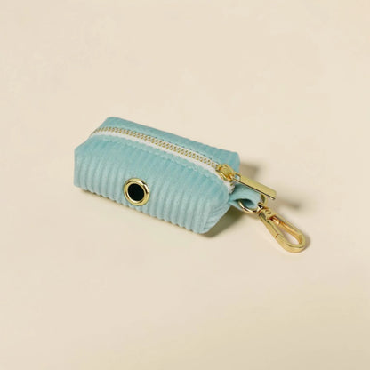 Soft mint green dog poop bag holder with gold zip and clip on a beige background