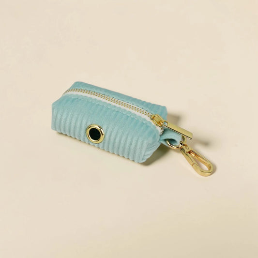 Soft mint green dog poop bag holder with gold zip and clip on a beige background