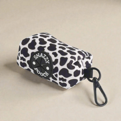 Cow print poop bag holder with 'Snazzy Pooch' logo on a beige background