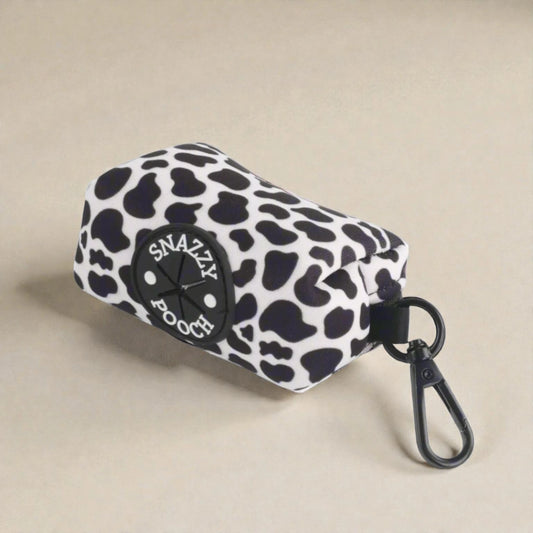 Cow print poop bag holder with 'Snazzy Pooch' logo on a beige background