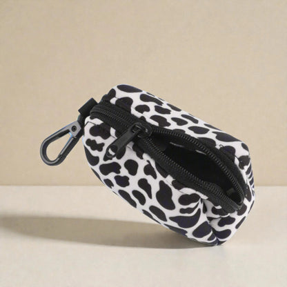 Dog poop bag holder with black and white pattern and a clip on a beige background