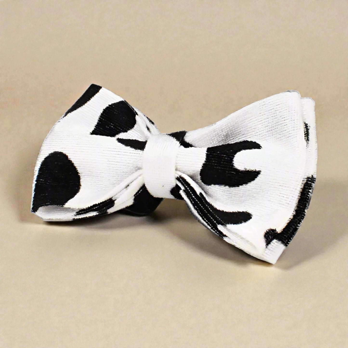 Black and white cow print tie on a beige background