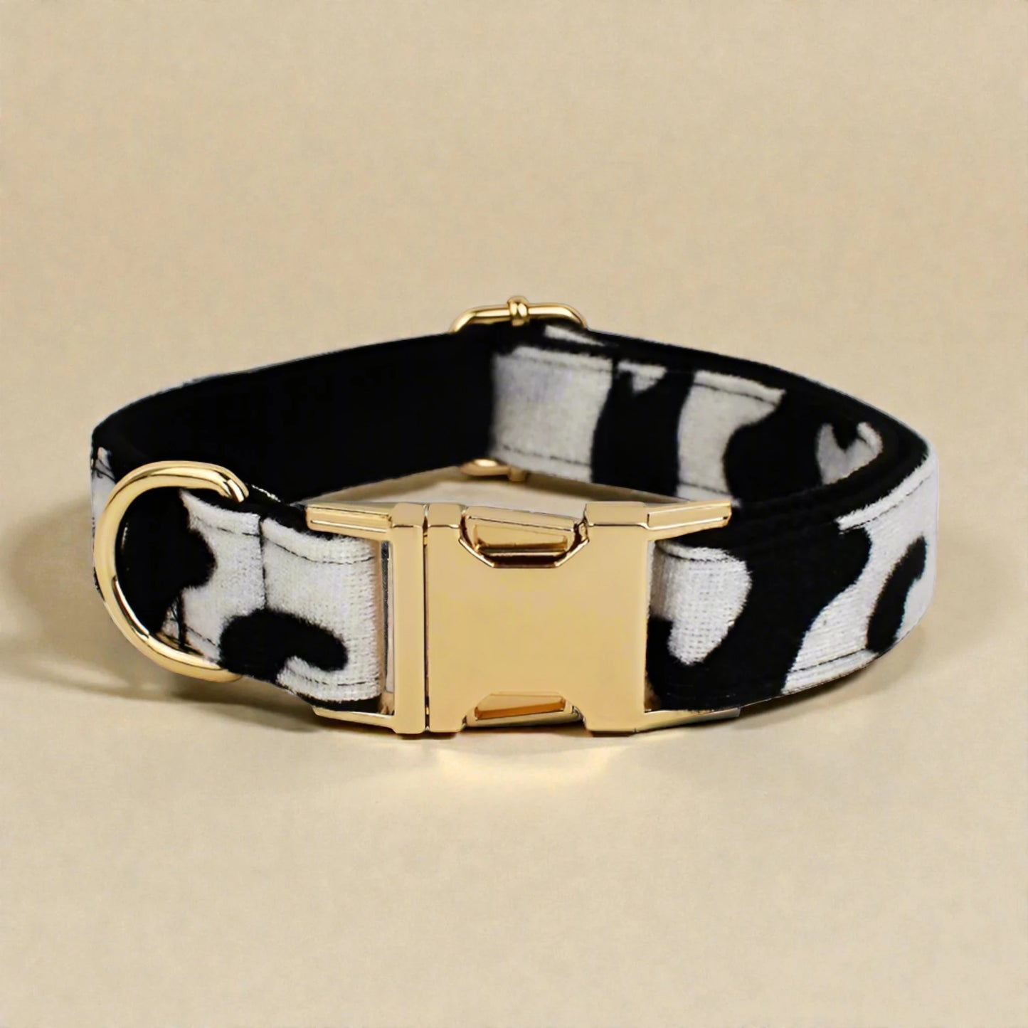 Dog collar with black and white pattern and gold buckle on beige background