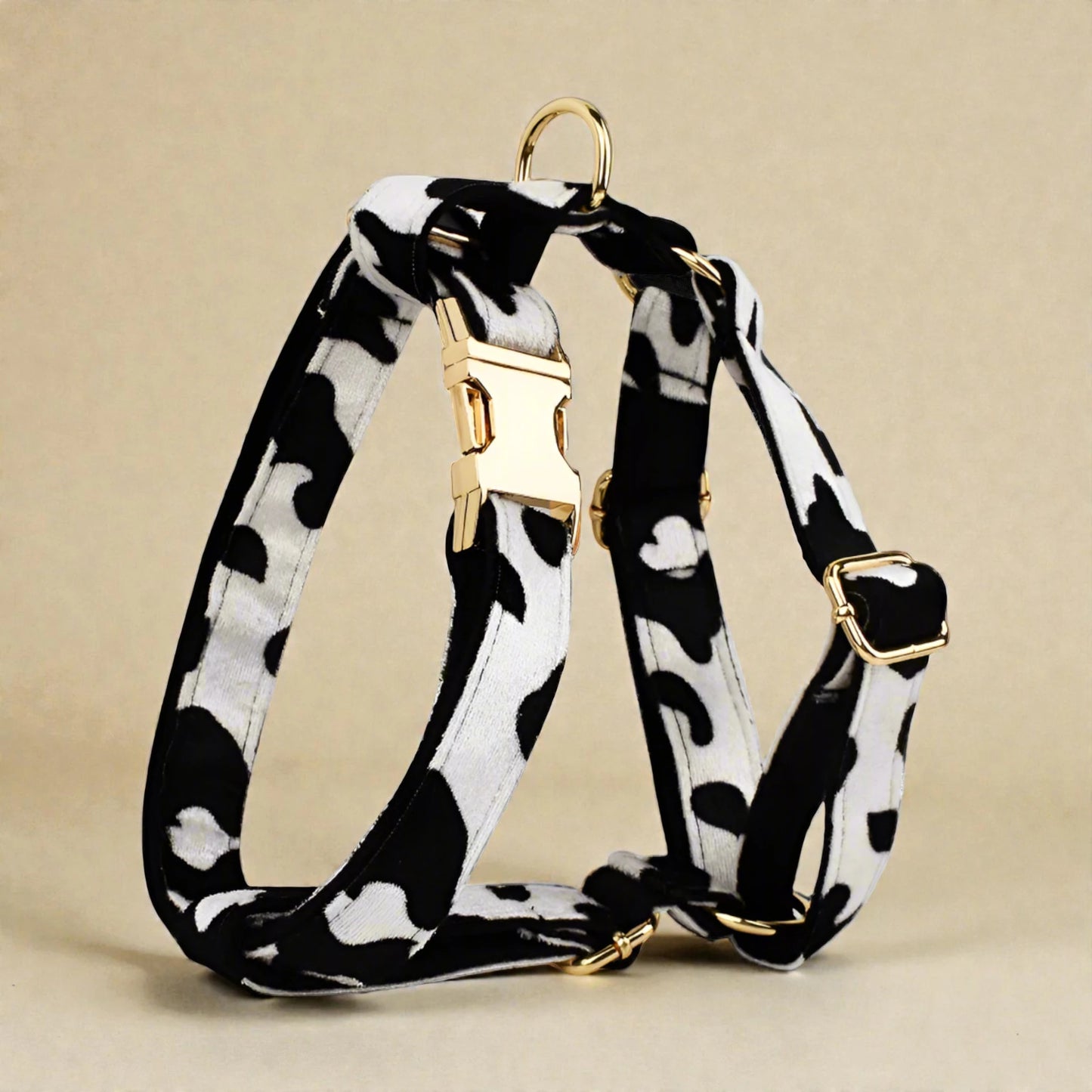 Black and white patterned dog harness with gold hardware on a beige background