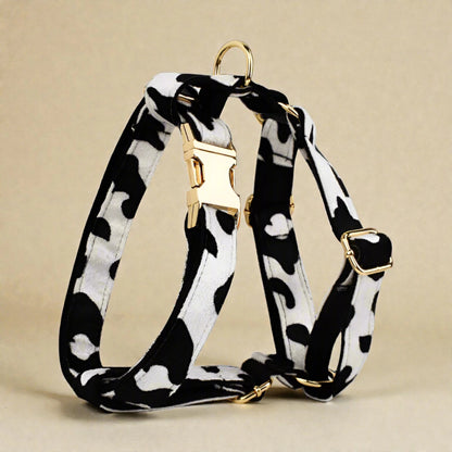 Black and white patterned dog harness with gold hardware on a beige background