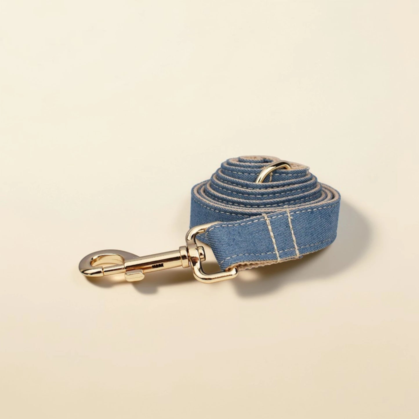 Denim tan dog lead with gold hardware on a beige background
